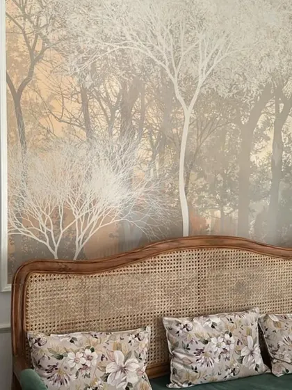 A serene, misty forest mural creates a peaceful backdrop behind a rattan sofa, perfectly complementing the natural textures in the room.