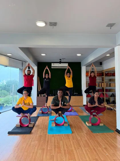A group of students demonstrates various balancing poses on yoga wheels, showcasing the diversity of practice within a single class.