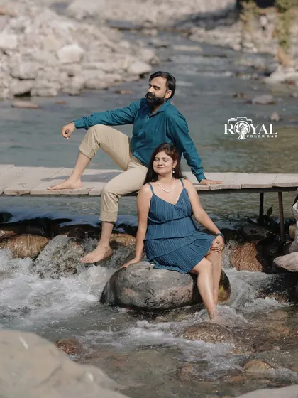 A lovely shot of a couple sitting by a small cascade, dipping their feet in the water, capturing a moment of peaceful connection.