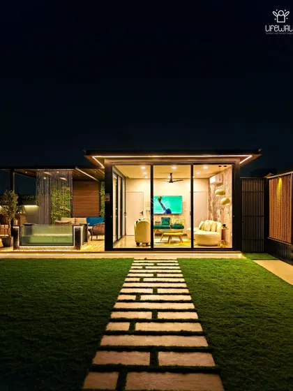 A wide shot of a completed project, showing the glass house, the glass-walled pool, and the stone pathway leading through the artificial grass lawn.