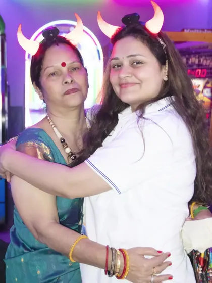 Two women wearing fun, light-up horns embrace for a photo at a party. We capture the playful and fun-loving spirit of your celebration.