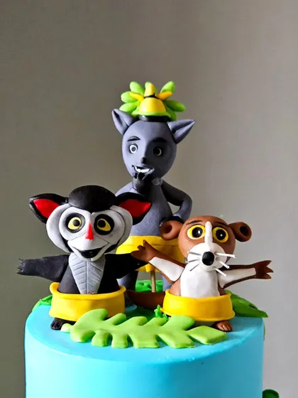 A detailed view of the handcrafted toppers of King Julien, Mort, and Maurice from the Madagascar cake. Each character is sculpted to capture their unique personality.