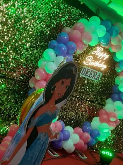 A Disney's Aladdin-themed birthday party featuring a Princess Jasmine cutout. The balloon arch and sequin backdrop create a vibrant and fun photo corner.