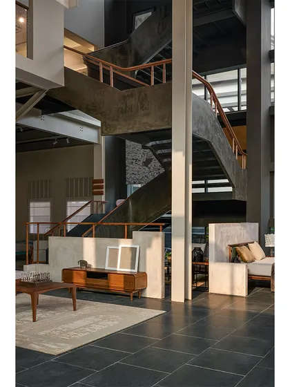 The monumental staircase acts as a central feature in the showroom, highlighting the building's structure while the soft texture of the ferrocement railing adds a tactile quality to the journey between floors.