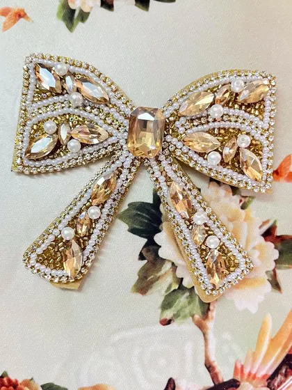 The gold embellished bow adds a touch of warmth and luxury, perfect for a wedding or festive occasion.