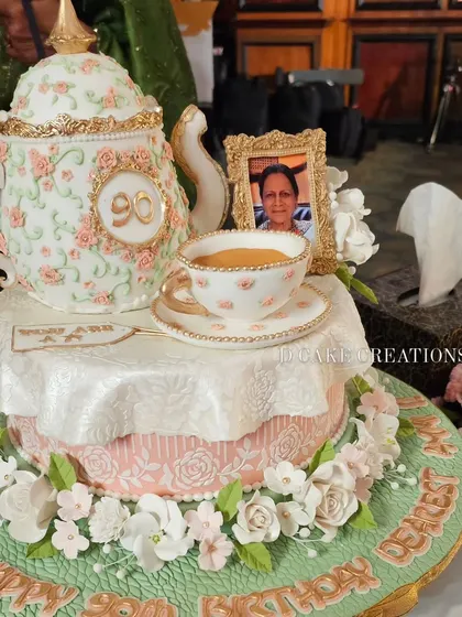 A detailed shot of the elegant teapot cake for Zeenat Hussain's 90th birthday. The cake features a classic floral design, a personalized tag, and an edible framed photo to make it extra special.