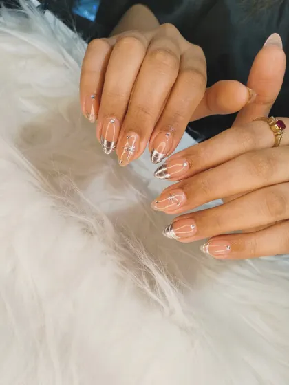 A celestial-inspired design with a sheer nude base, chrome silver tips, and delicate, sparkling starbursts and dots.