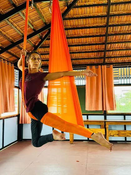 A student extends gracefully in the orange hammock, her focus and poise evident.