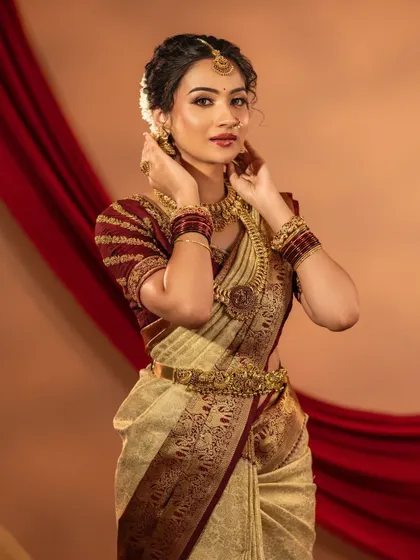 This traditional look is all about grace. The model is wearing a classic antique gold set with a choker and a coin haram (kasumalai), perfect for a Muhurtham or wedding photoshoot.