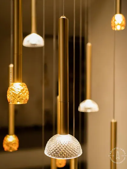 This cluster pendant features a mix of gold-toned rods with textured glass shades, some resembling pineapples and others simple domes. The combination creates a visually interesting and warm installation for any corner that needs a lift.