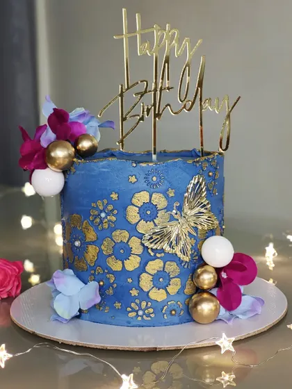 This royal blue and gold cake is a real showstopper. I used a gold floral and butterfly stencil to create an intricate pattern that stands out beautifully against the deep blue buttercream.