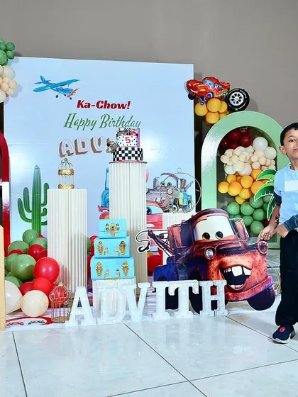 The birthday boy, Advith, looking stylish and happy in front of his custom Disney 'Cars' party setup.