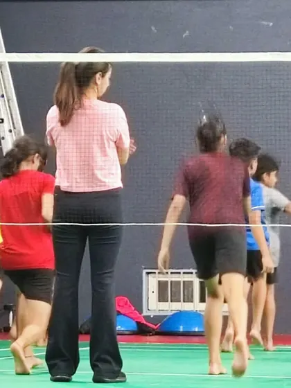Observing and guiding young badminton players during their on-court movement drills, focusing on agility and footwork.