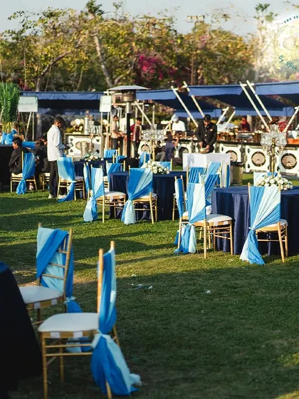 An outdoor Mehendi Sangeet with elegant table settings in shades of blue. The open air setup allows guests to enjoy the beautiful weather while celebrating.