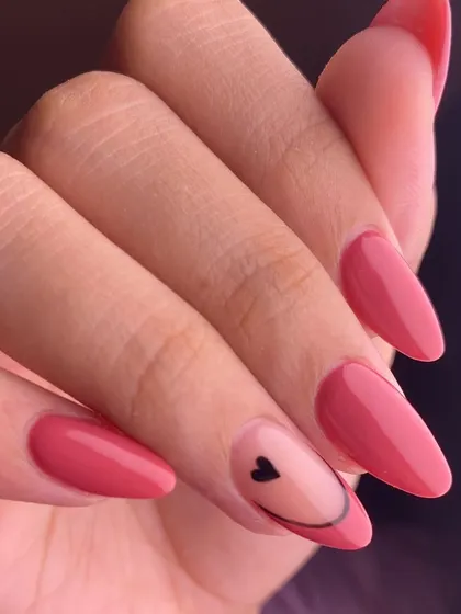 A simple and sweet design with a touch of personality. This manicure features a lovely solid pink color with a single accent nail showing a minimalist smiley face and heart.