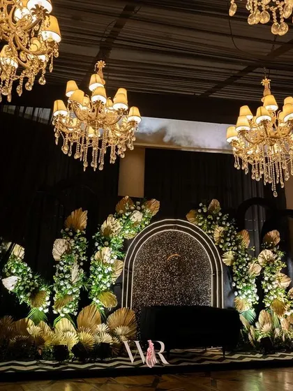 The stage for our Jazz Club theme featured a black sequined backdrop framed by white florals and golden palm leaves. The design is a nod to the glamour of the Art Deco era, creating a sophisticated focal point for the evening's events.