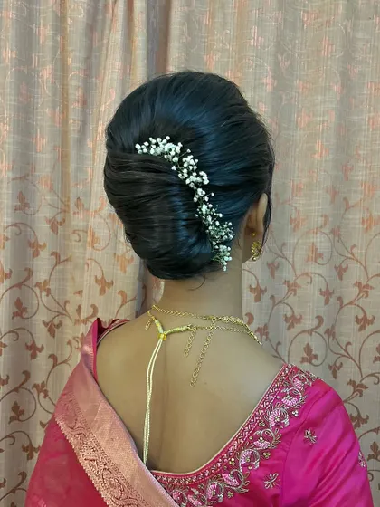 A sleek French twist style bun with a line of baby's breath, combining classic technique with a modern touch.