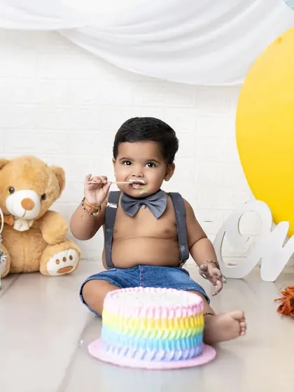 A slightly calmer moment during the cake smash, with a sweet, frosting-covered smile. The moon and stars backdrop adds a dreamy touch to this first birthday session.