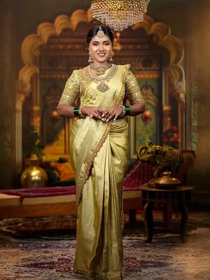 A full-length shot of a bride in a golden-yellow Kanjeevaram saree against a royal backdrop. This image captures the grandeur and elegance of a traditional South Indian wedding look.