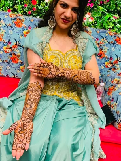 A beautiful bride at her mehndi ceremony, her hands posed to show the intricate peacock designs.