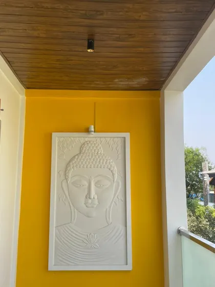 A beautiful white Buddha relief panel installed on a vibrant yellow accent wall in a balcony. This on-site image shows how we incorporate art and spirituality into our exterior and semi-exterior spaces.