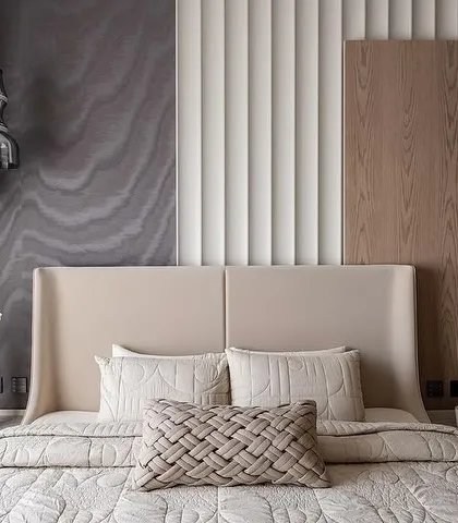 A bedroom by PKD Studio where a luxurious palette is layered with tactile materials. Our dark, subtly patterned wallpaper is paired with a fluted panel and wood, creating a space that exudes stillness and tranquility.