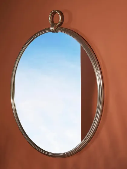 A silver-framed mirror with a unique ring hanger. The reflection of the blue sky adds a pop of color and an element of surrealism to this otherwise simple product shot.