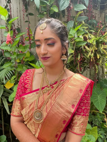 The complete look against a natural backdrop. The makeup stands out beautifully, enhancing her features while complementing the rich colors of her saree.