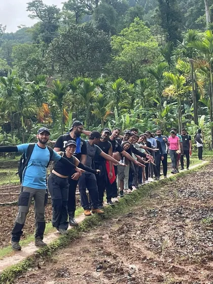 A team lines up on a narrow path during the Kodachadri trek. The journey takes you through diverse landscapes, from dense forests to open fields.