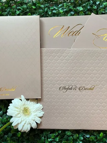 For a minimalist and modern look, this booklet-style invitation uses high-quality textured paper in a neutral beige tone. The couple's names are elegantly printed in gold foil, creating a simple yet luxurious feel.