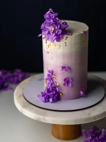A beautiful example of a modern tall tiered cake with a delicate purple ombre effect and floral decorations. In my workshop, I teach you how to achieve this smooth finish with Swiss meringue buttercream.