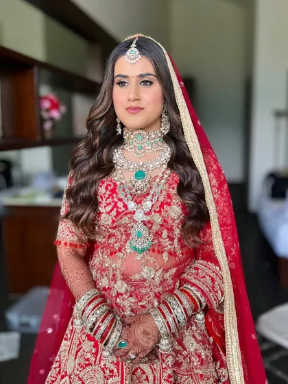 A full view of this regal bride. Her stunning red lehenga and grand jewelry were paired with a sophisticated makeup look and voluminous waves.