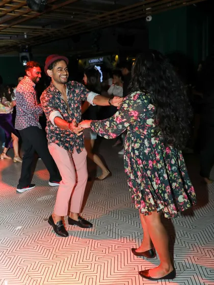 A fun and energetic couple dancing with enthusiasm. The floral dress adds to the cheerful vibe.