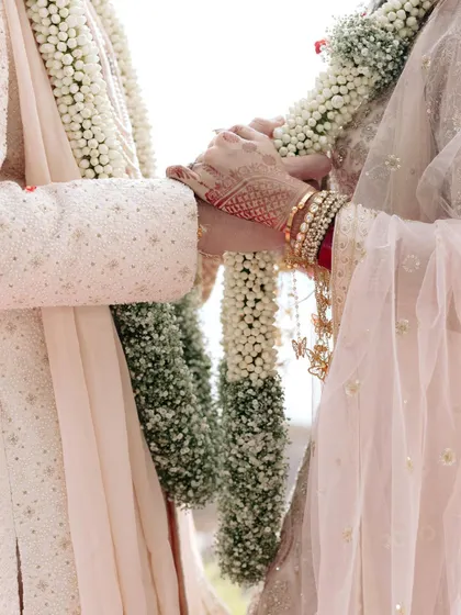 A close-up shot focusing on the couple's hands during the garland exchange, symbolizing their union.
