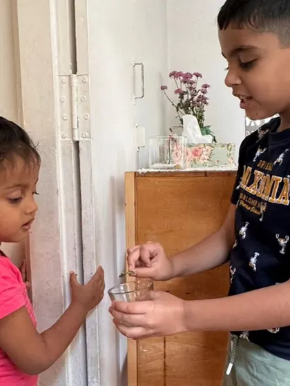 A moment of spontaneous science. An older child shows a younger one the tiny insect eggs he discovered on a leaf, sharing his excitement and knowledge in our multi-age classroom.