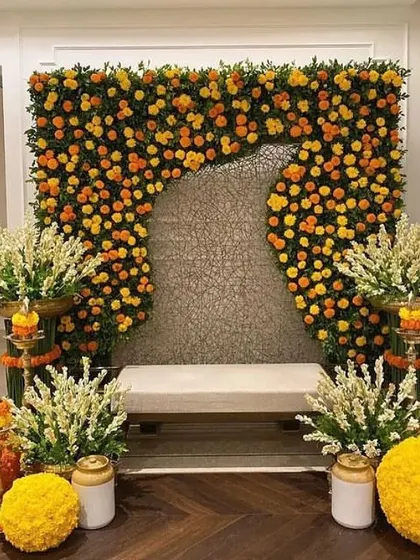 A unique Haldi backdrop featuring a wall of marigolds with a modern, abstract cutout. This design blends traditional flowers with contemporary art.