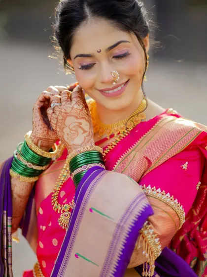 A close-up focusing on the delicate details. You can see the intricate henna design, the classic green bangles, and the soft, shimmering eyeshadow that completes this bridal look.