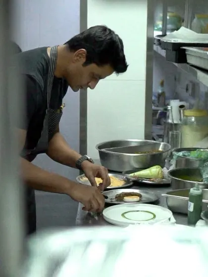 A candid shot of me in the kitchen, focused on the intricate details of plating a dish for the 'Modern Luxury' dinner series in Delhi.