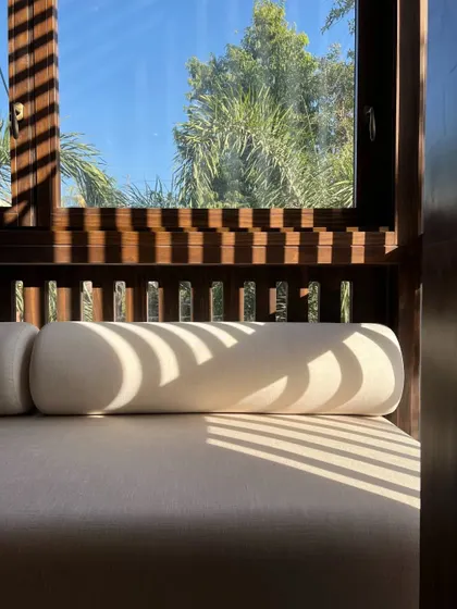The beautiful patterns cast by the sun through the 'jharokha' screens fall upon a cushioned sofa, illustrating how our designs use natural light as a dynamic material.