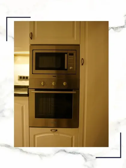 We use only the best. This close-up shows the built-in microwave and oven, perfectly fitted into our custom cabinetry, offering a blend of high-end functionality and elegant design.