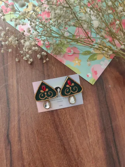 A pair of hand-painted earrings in a unique triangular shape. The dark green fabric is decorated with a red and gold motif and a single mirror drop.