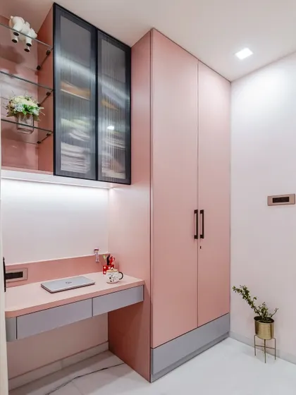 This shot shows the full floor-to-ceiling storage unit, which combines the study nook with a matching pink wardrobe. Using a single color for all the furniture gives the small room a cohesive and less cluttered appearance.