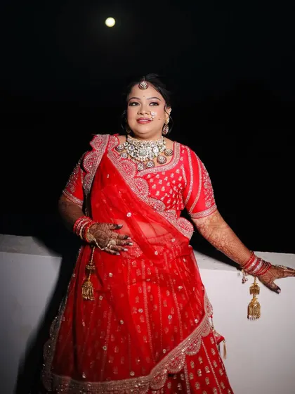 A full-length shot of the bride against the night sky, looking absolutely regal in her red lehenga.