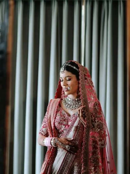 A reflective bridal portrait, capturing the bride's image in a mirror as she adjusts her jewelry.