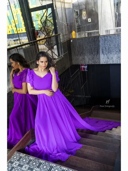 A beautiful shot of a flowing purple gown with a long, dramatic train. The flutter sleeves and lightweight fabric are designed to create a sense of movement and romance.