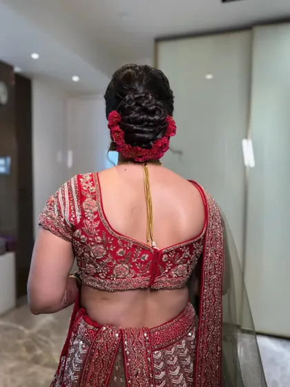 A final look at the intricate, braided bun adorned with a traditional red cockscomb gajra. This is a classic choice for a bride wanting a secure and ornate hairstyle for her pheras.
