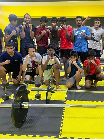 A group of our younger and adult members posing after a tough strength and conditioning session, with a barbell and weights in the foreground.