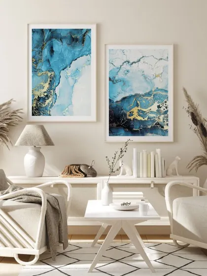 Our set of two indigo and gold alcohol ink prints, shown here in a coastal or Scandi-boho living room. The white wood frames keep the look light and airy, letting the abstract art be the focus.