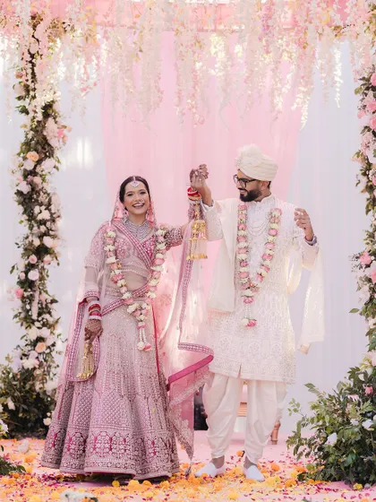 A celebratory portrait of the couple after their Varmala ceremony, standing together under a beautiful floral arch.