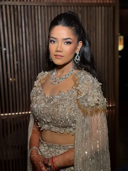 A sultry and luminous cocktail look designed for dusky skin tones. This makeup channels a radiant, high-fashion energy with glowing highlights and warm tones to beautifully complement a jeweled gold ensemble.